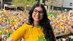 Eduarda Campopiano sorrindo durante manifestação, com multidão ao fundo