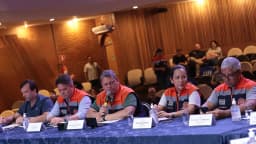 Governador Tarcísio de Freitas fala ao microfone durante reunião oficial, usando colete da Defesa Civil