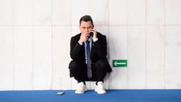 Senador Cleitinho, candidato ao governo de Minas Gerais, agachado ao telefone em corredor do Senado (foto de arquivo)