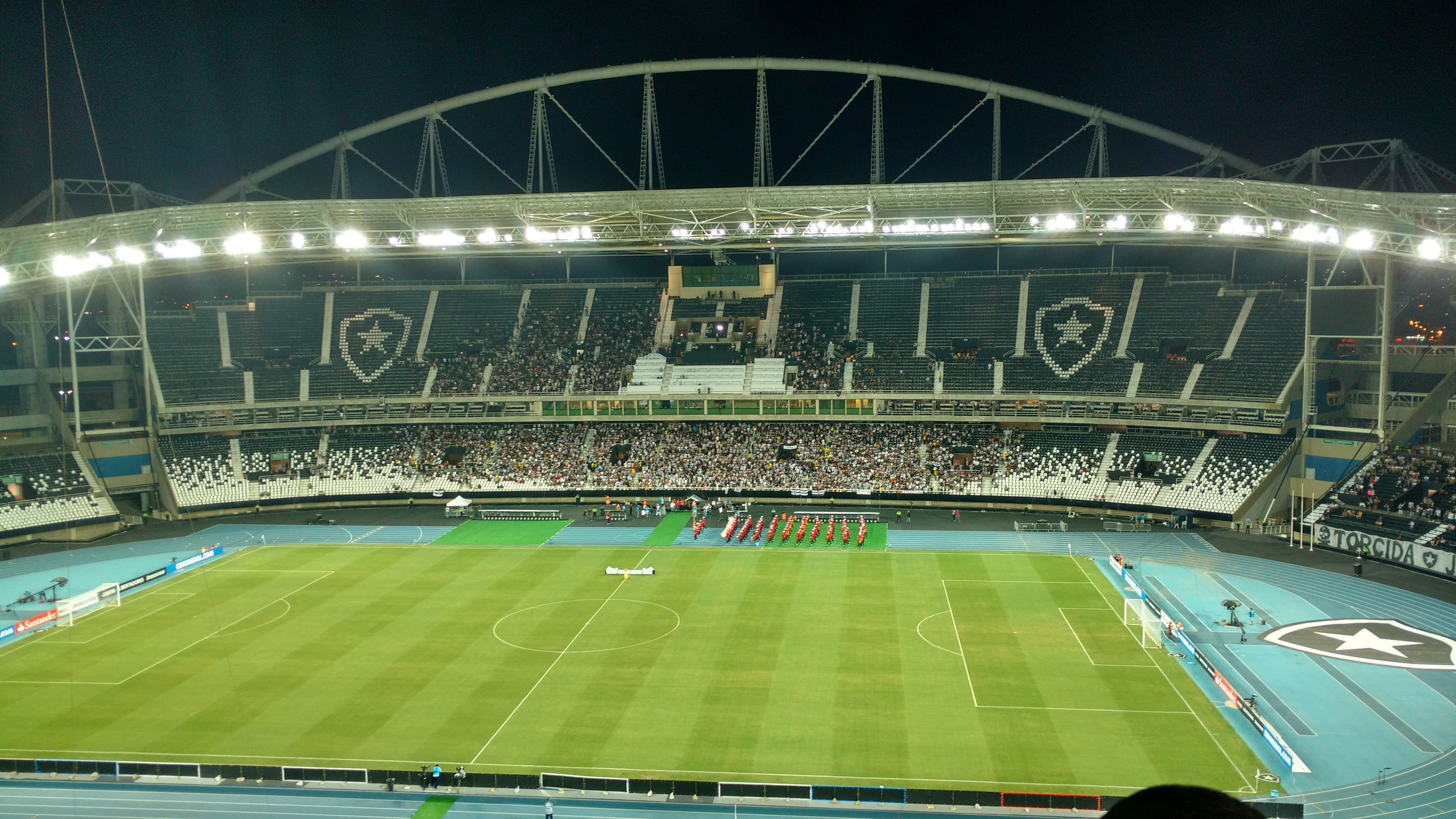 Estádio Nilton Santos à noite, em jogo do Botafogo, com torcida nas arquibancadas