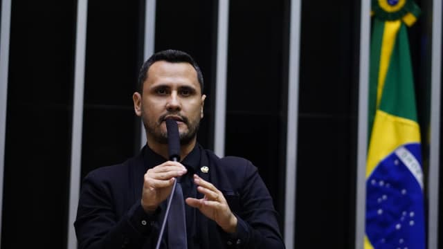 Cleitinho Azevedo discursa no plenário com a mão levantada, microfone à frente