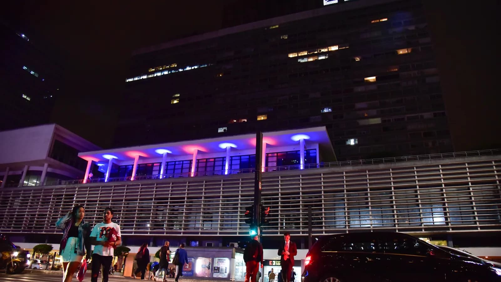 Fachada do consulado dos Estados Unidos em São Paulo durante evento, com pessoas na calçada à noite