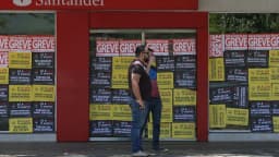 Homens passam em frente a agência bancária com cartazes de bancários em greve (foto de arquivo)