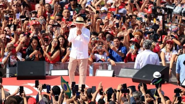 Lula discursa em palco vermelho cercado por apoiadores em primeiro ato de campanha