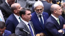 Flávio Bolsonaro fala ao microfone em plenário, cercado por parlamentares, em foto de arquivo