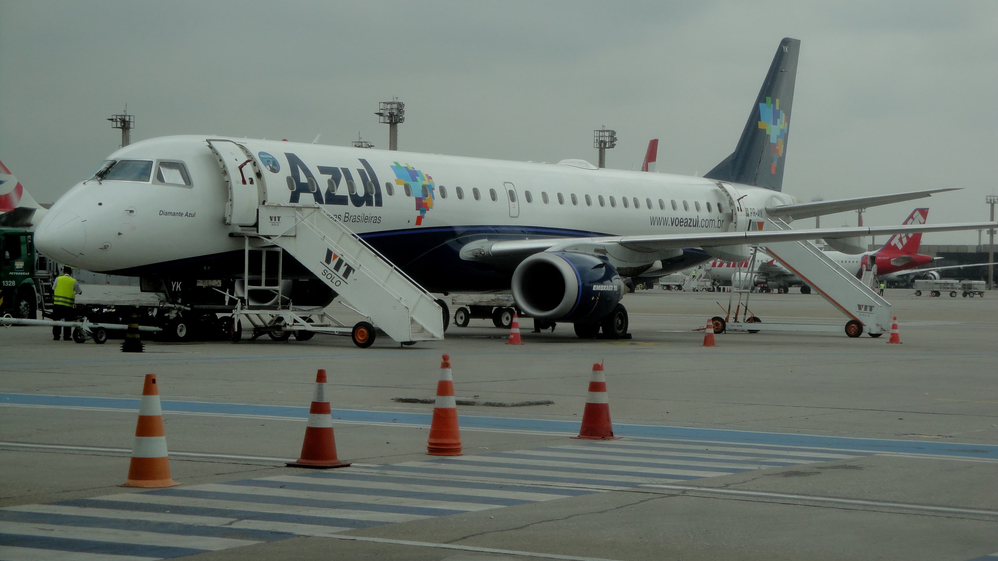 Avião da Azul estacionado no pátio do Aeroporto de Guarulhos, com equipe de solo ao lado, foto de arquivo que ilustra o custo do combustível de aviação