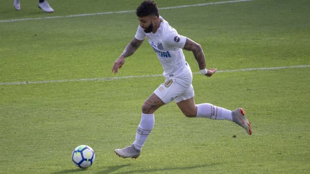 Gabigol, atacante do Santos, conduz a bola durante partida, uniforme branco