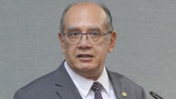 Ministro Gilmar Mendes gesticula durante discurso, de terno cinza e óculos