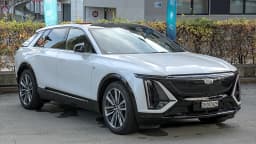 Cadillac Lyriq branco estacionado em área urbana, visto de frente e de lado