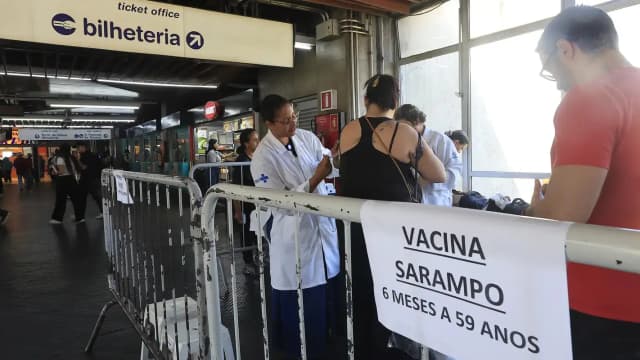 Profissional de saúde atende pessoas em posto de vacinação contra o sarampo