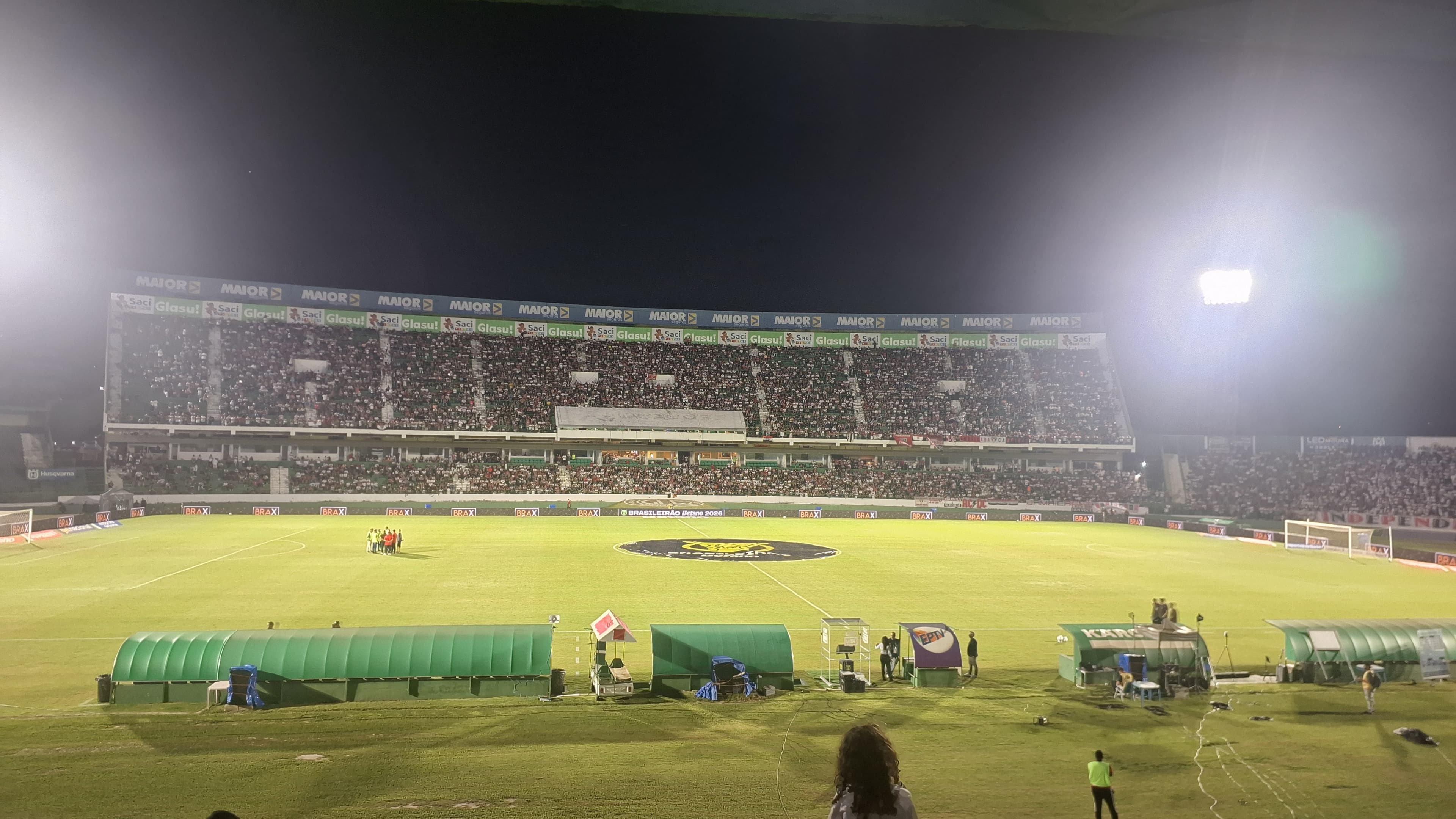 Estádio lotado durante partida do Brasileirão 2026, com jogadores reunidos no campo antes da bola rolar