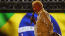 Lula discursa em microfone durante ato de campanha eleitoral, com bandeira do Brasil ao fundo (foto de arquivo)