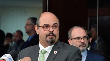 Mateus Simões, de terno cinza e gravata verde, fala a jornalistas diante de microfones em entrevista coletiva; imagem de arquivo de abril de 2024