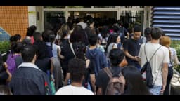 Candidatos de costas entram em fila para local de prova de concurso público