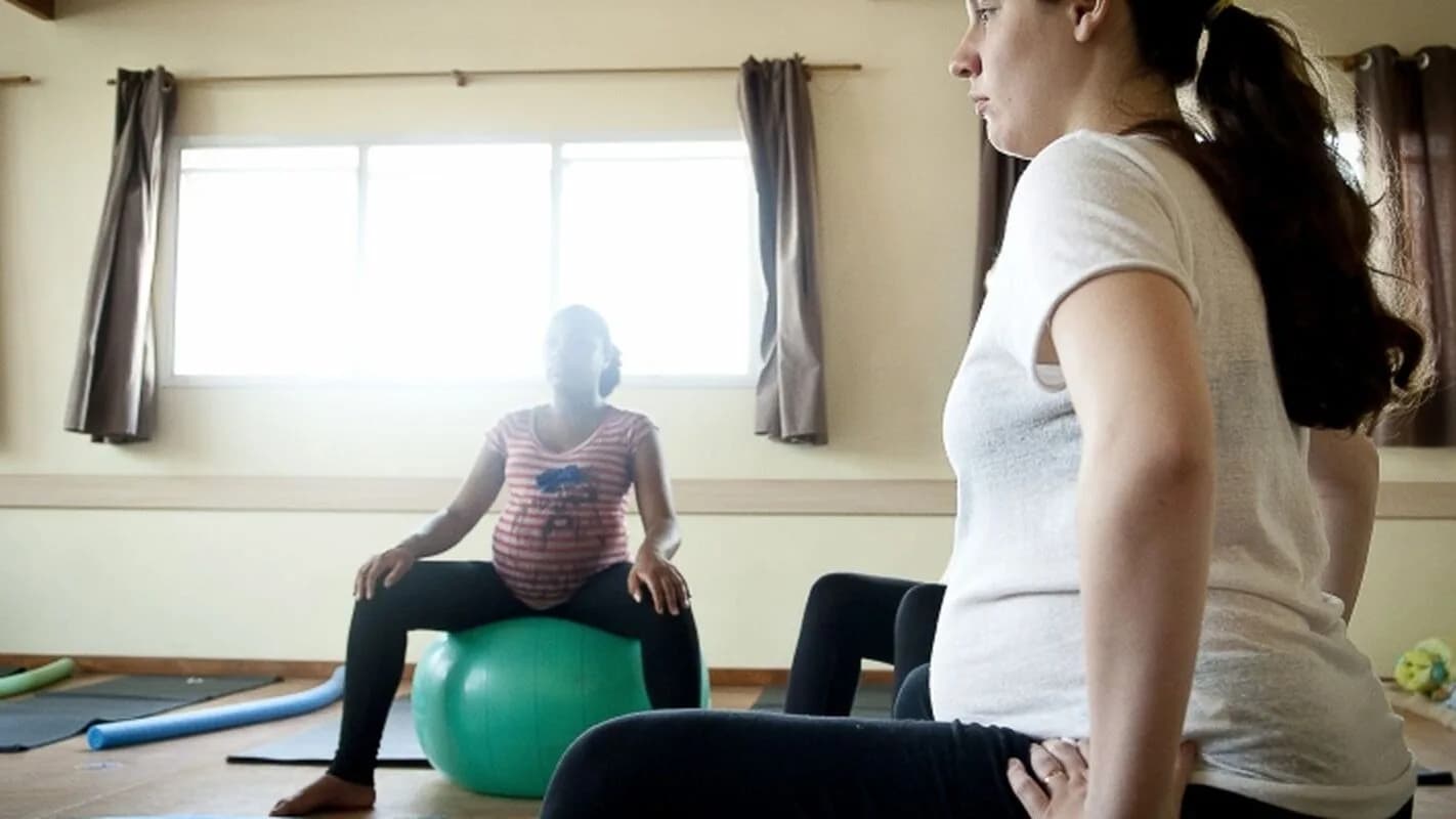 Mulher grávida faz exercício sobre bola de pilates durante acompanhamento pré-natal