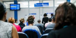 Sala de espera lotada de segurados aguardando perícia médica em agência do INSS