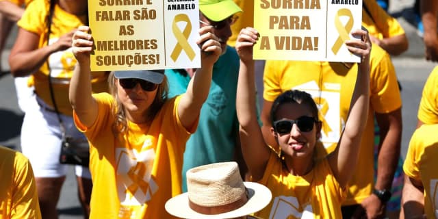 Participantes de caminhada do Setembro Amarelo seguram cartazes de incentivo à vida