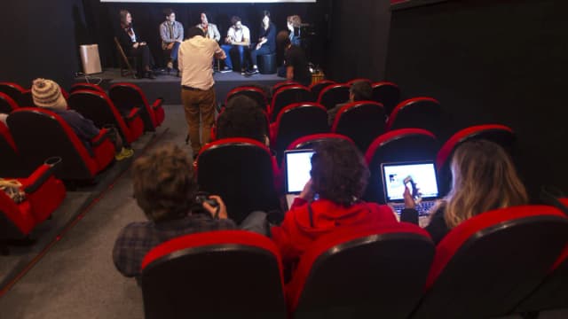 Jovens profissionais usam notebooks e celulares lado a lado durante evento
