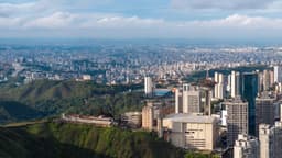 Vista aérea panorâmica de Belo Horizonte, com prédios e a Torre da Calouste ao fundo