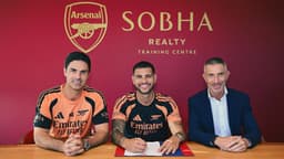 Bruno Guimarães sorri ao assinar contrato com o Arsenal, ao lado do técnico Mikel Arteta e do diretor esportivo Andrea Berta