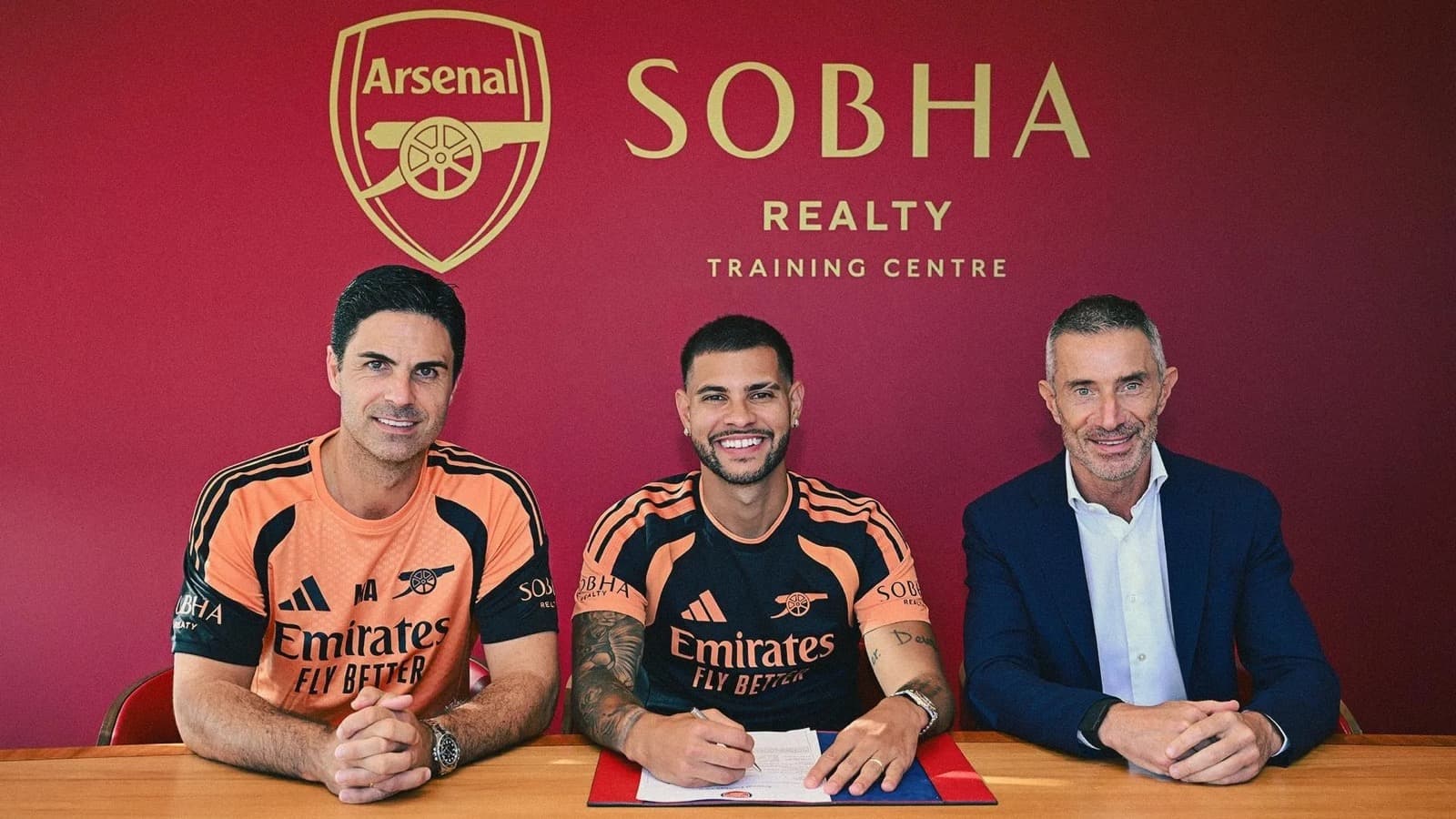 Bruno Guimarães sorri ao assinar contrato com o Arsenal, ao lado do técnico Mikel Arteta e do diretor esportivo Andrea Berta