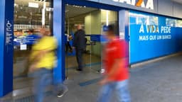 Entrada de agência bancária com pedestres passando, foto de arquivo