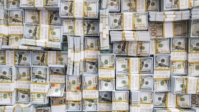 Painel eletrônico com cotações da Bolsa de Valores, com pessoas observando os números