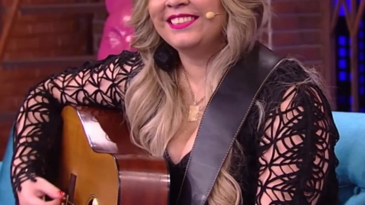 Marília Mendonça sorrindo e tocando violão em programa de TV