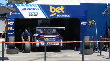Mecânico empurra pneu ao lado de carro da Stock Car Pro Series no box (foto de arquivo)