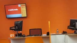 Painel de senhas e monitor em agência do banco Itaú, com o slogan "e muito mais" na tela, foto de arquivo