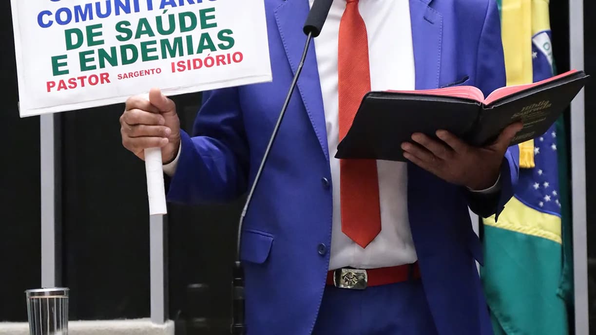 Pastor Sargento Isidório discursa no plenário da Câmara dos Deputados segurando cartaz e Bíblia