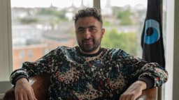 Retrato de Mustafa Suleyman, CEO da Microsoft AI, sentado em ambiente interno