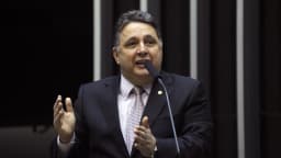 Anthony Garotinho discursa em tribuna com microfone, de terno escuro