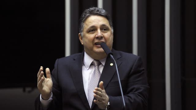 Anthony Garotinho discursa em tribuna com microfone, de terno escuro