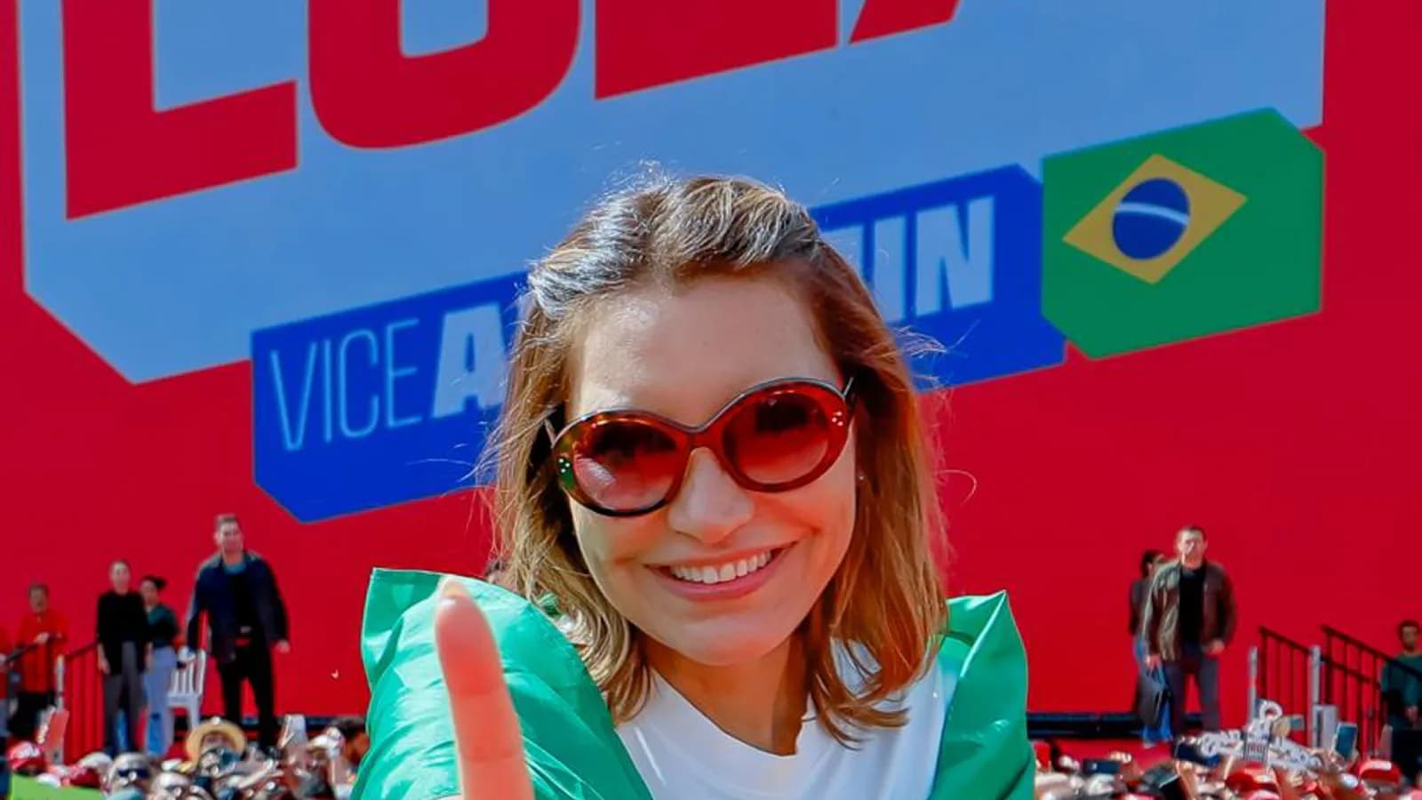 Apoiadora grava com o celular o lançamento da campanha de reeleição de Lula, com telão e multidão ao fundo