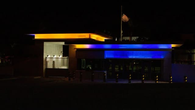 Portaria da Embaixada dos Estados Unidos em Brasília à noite, com a bandeira americana hasteada