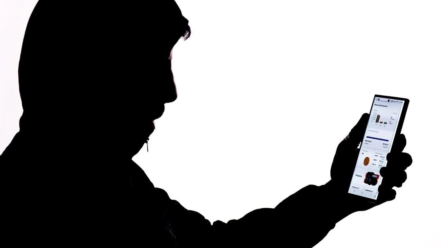 Silhueta de pessoa usando celular com informações de cibersegurança, foto ilustrativa