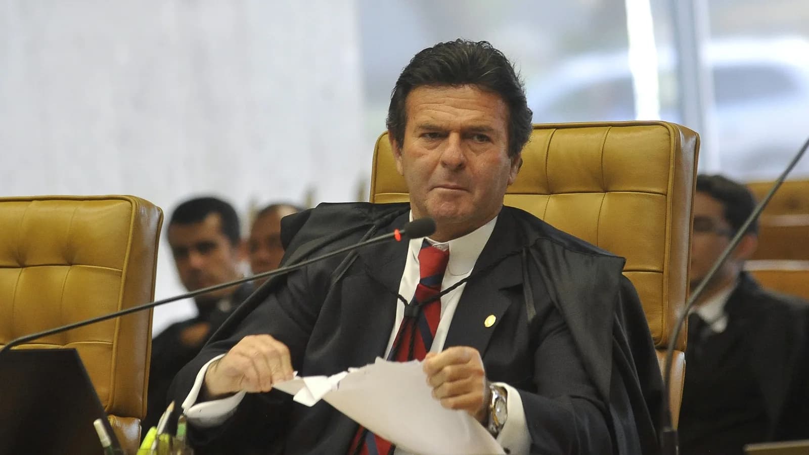 O ministro Luiz Fux, do STF, usa toga preta e gravata vermelha durante sessão de julgamento no plenário do tribunal
