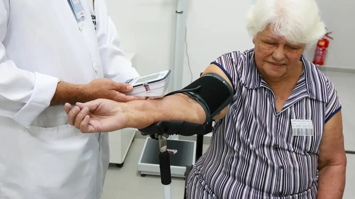 Idosa tem a pressão aferida por profissional de saúde