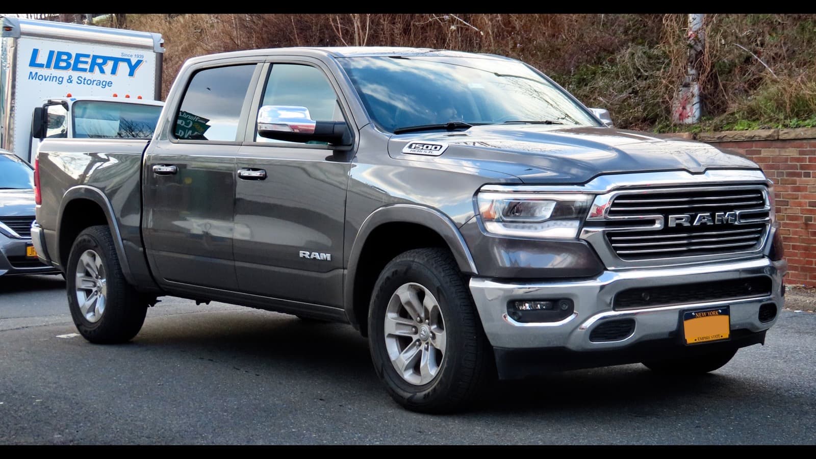 Picape Ram 1500 cinza fotografada em rua nos Estados Unidos, mostrando grade frontal com a marca Ram e o emblema 1500 Hemi 5.7L no capô