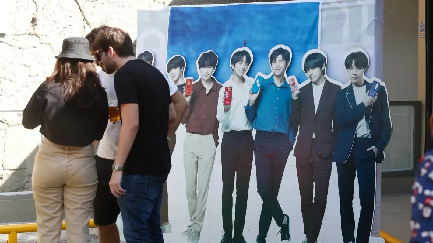 Fãs tiram foto com painel do grupo BTS