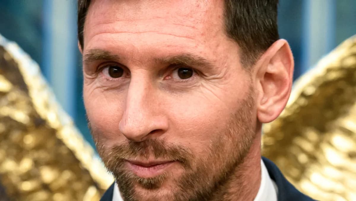 Lionel Messi sorri em evento formal, vestindo terno