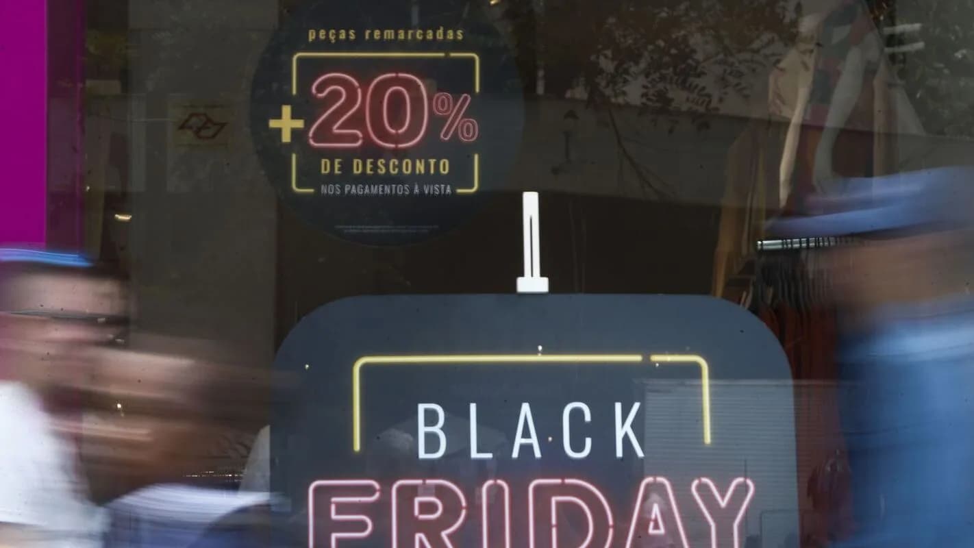 Vitrine de loja com cartaz de desconto de Black Friday e pessoas passando em movimento