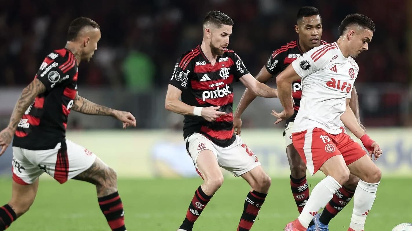 Jogador do Internacional disputa a bola com adversários do Flamengo em campo