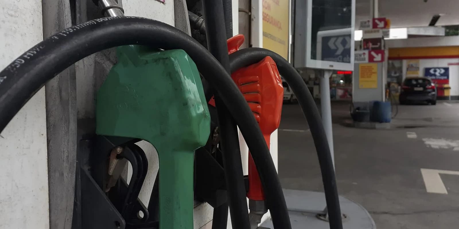 Bicos de bomba de combustível verde e vermelho em posto de gasolina