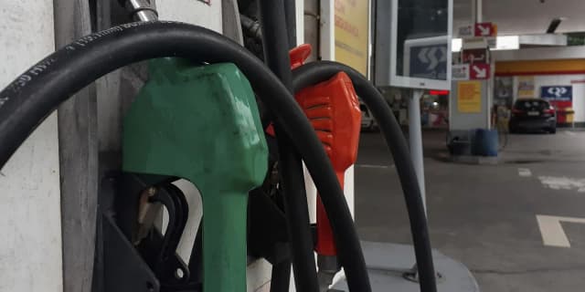 Bicos de bomba de combustível verde e vermelho em posto de gasolina