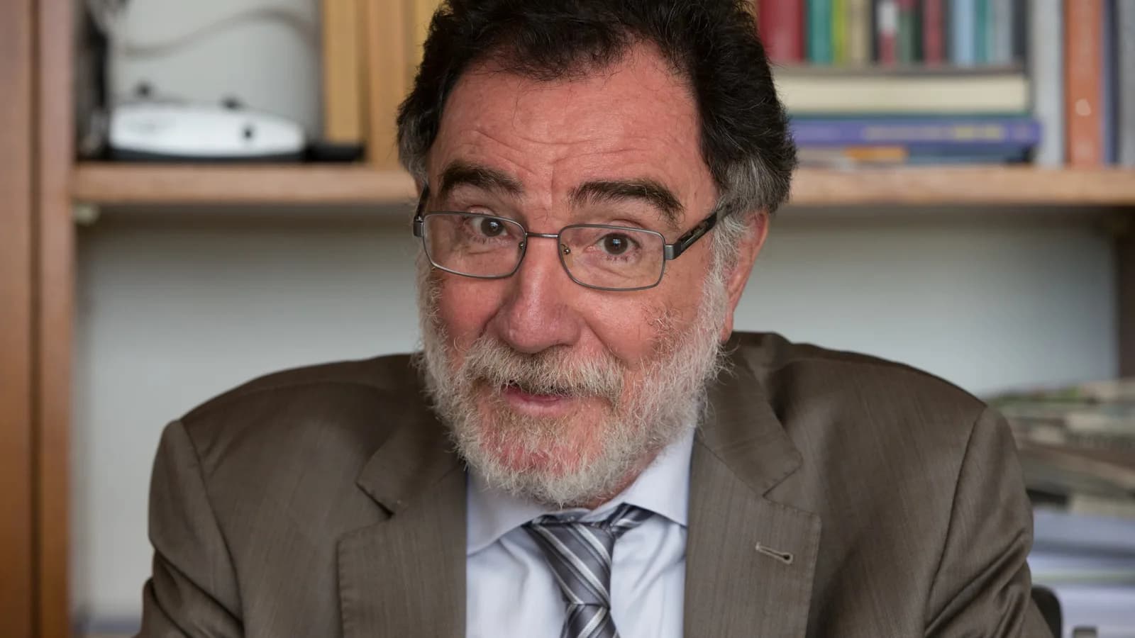 Patrus Ananias, candidato do PT ao governo de Minas Gerais, em entrevista de terno em escritório com estante de livros ao fundo