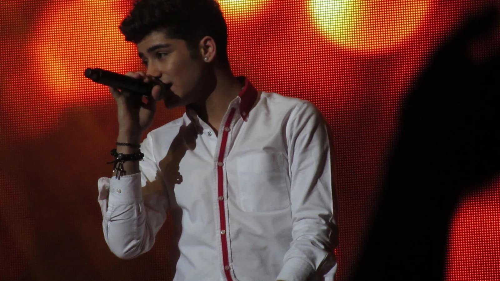Zayn Malik cantando ao microfone durante show, foto de arquivo
