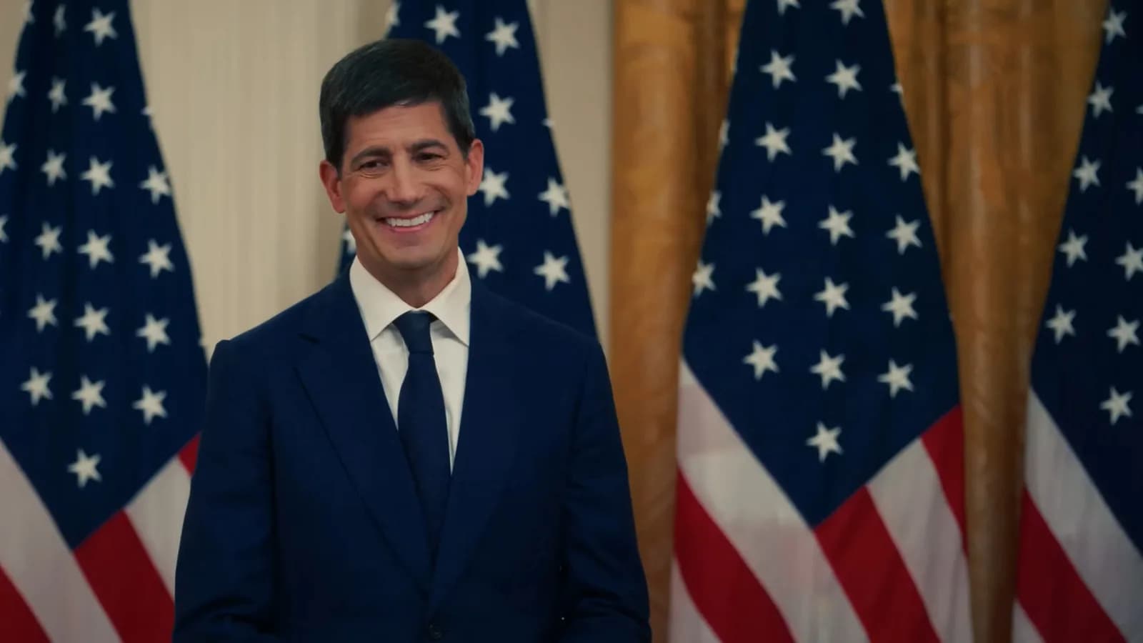 Kevin Warsh, presidente do Federal Reserve, sorri em cerimônia na Casa Branca com bandeiras dos EUA ao fundo