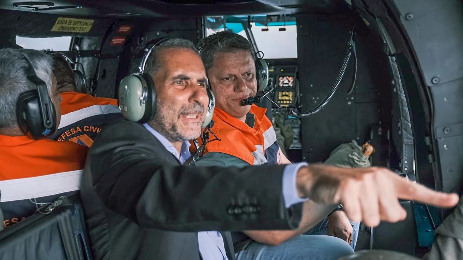 Governador Tarcísio de Freitas dentro de helicóptero, apontando para fora durante sobrevoo de área atingida, foto de arquivo de 2023